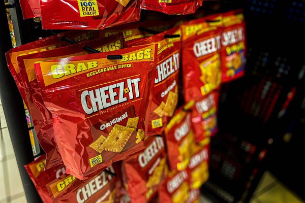 Saint Louis, MOOct 18, 2020; red and yellow flexible packaging bag marked with the brand Cheez It snack crackers, a Kellogg company product, hang on display for purchase 