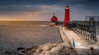 Grand Haven, Ortaçağ 15, 2019, bulutlu kış gününde Batı Michigan kıyıları boyunca Grand River körfezindeki beton iskelede duran kırmızı deniz feneri ve sis borusu. 