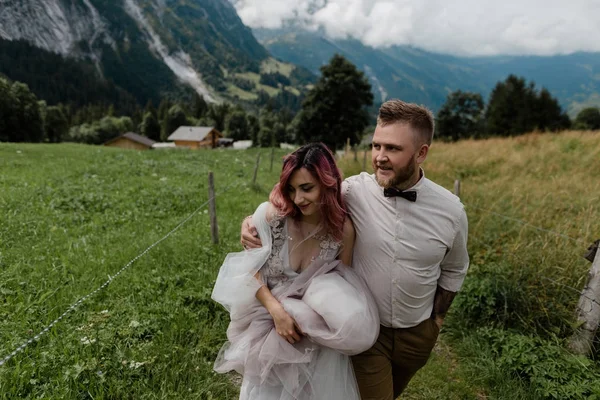 愉快的年轻婚礼夫妇拥抱和一起漫步在美丽的高山谷 — 图库照片