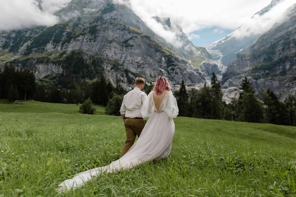 Achteraanzicht Van Bruid Bruidsjurk Bruidegom Hand Hand Lopen Groene Berg — Stockfoto