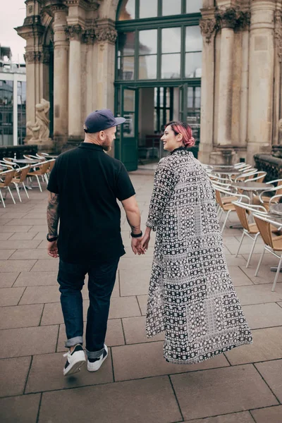 Visão traseira do jovem casal feliz de mãos dadas e andando perto de edifício antigo em Dresden, Alemanha — Fotografia de Stock