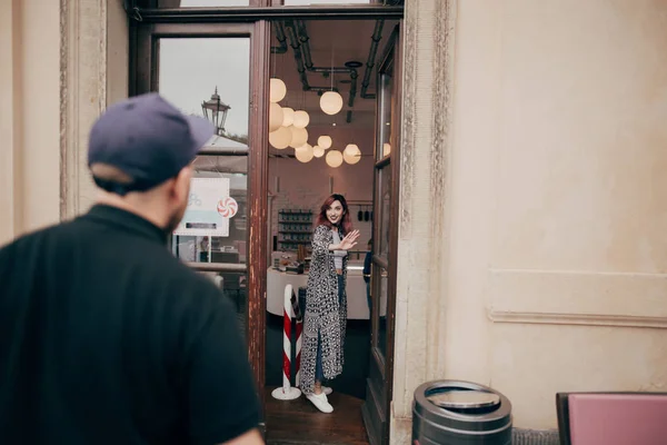 Вид сзади молодого человека, смотрящего на красивую подругу, стоящую в кафе в центре города — стоковое фото
