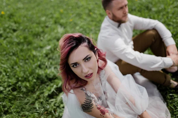 Beautiful bridal couple sitting on green grass — Stock Photo