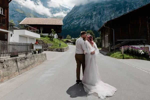 Visão traseira do casal abraçando e beijando na estrada na cidade em Alpes — Fotografia de Stock