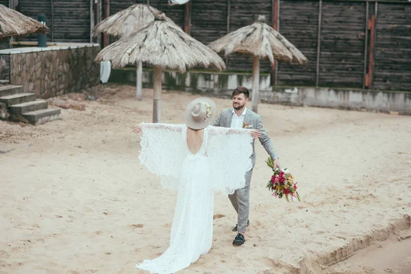 Beautiful happy bridal couple in bohemian style on beach — Stock Photo