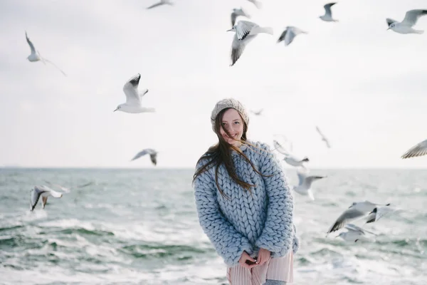 Attraente sorridente ragazza in posa sulla riva del mare invernale con gabbiani — Foto stock