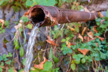 Paslı demir tüpten akan su.