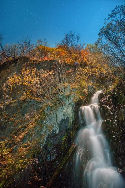 Ночной вид осеннего леса на горы и водопад — стоковое фото