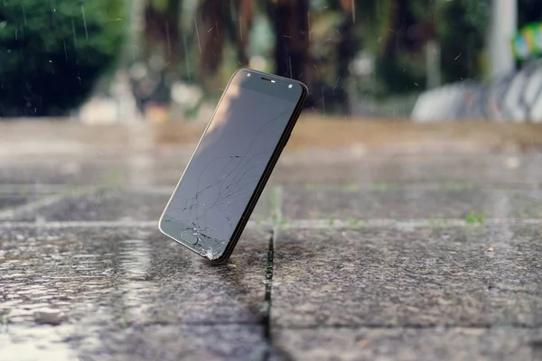 Smartphone faller och kraschar på våt trottoar — Stockfoto