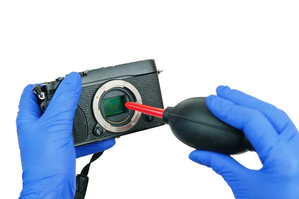 hands cleaning digital camera sensor from dust with air blower