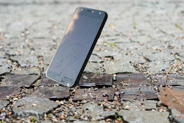 Smartphone cayendo y estrellándose en el suelo húmedo — Foto de Stock