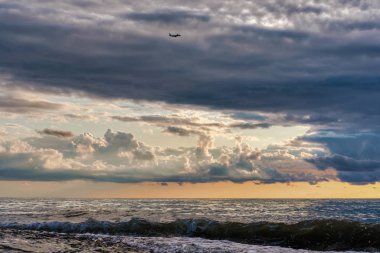 Dramatik bulutlu gün batımı gökyüzünde bir uçak 