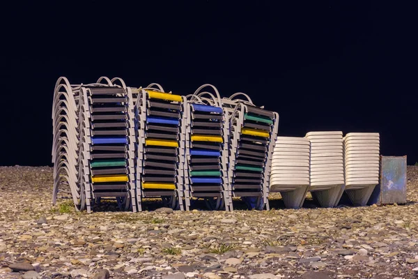 Chaise lounges de playa apilados en fila en la playa de noche — Foto de Stock