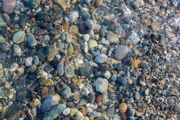 Rocas coloridas y guijarros bajo el agua clara — Foto de Stock