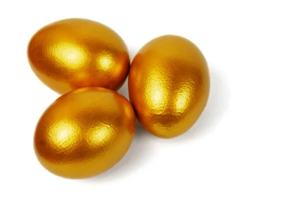 Zlaté velikonoční vajíčka na bílém pozadí — Stock fotografie