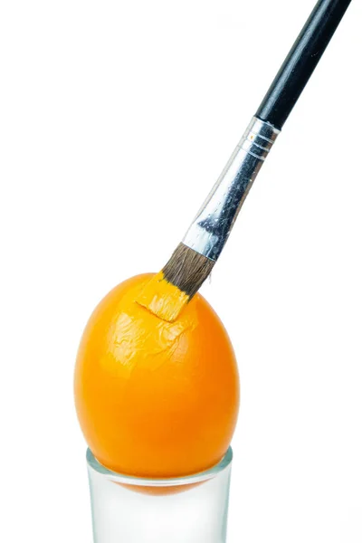 Štětec malování velikonoční vejce s oranžovou barvou — Stock fotografie