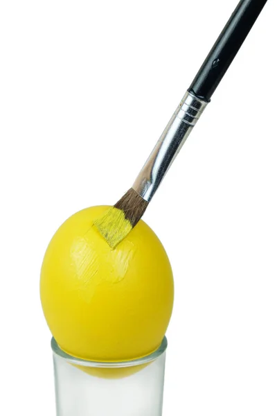 Пензлик розмальовує великоднє яйце жовтою фарбою — стокове фото