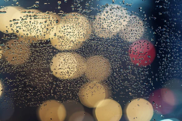 Gotas de água no vidro com luzes embaçadas coloridas fundo — Fotografia de Stock