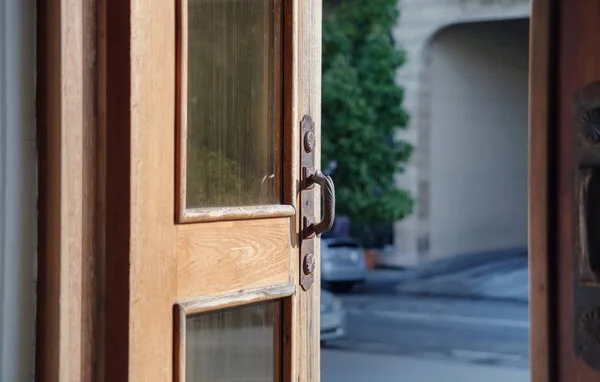 An open wooden door with old metal door handles
