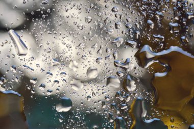 Su, mavi, beyaz ve altın renkleri olan gümüş soyut bir arkaplana düşer