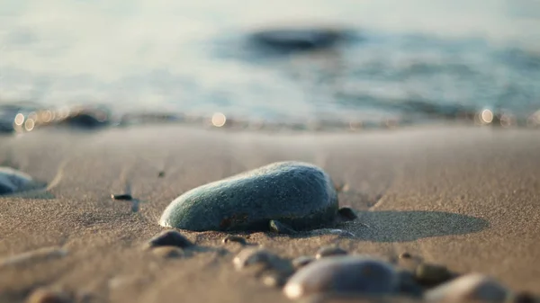 Nasse Kieselsteine Auf Dem Sand Mit Verschwommenem Hintergrund Kleiner Wellen — Stockfoto