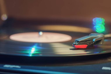 Dönen siyah vinil plaklı, yeşil ve mavi ışıkları yansıtan Retro kayıt çalar
