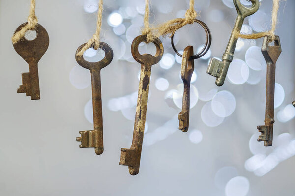Old rusty keys hanged on the ropes with blurred lights bokeh background, selective focus