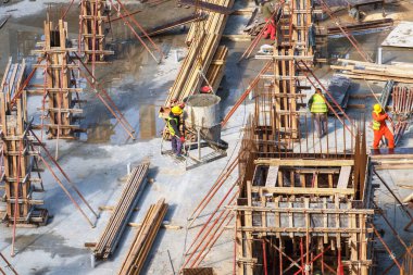 İşçiler inşaat sahasına beton kolon döküyorlar.