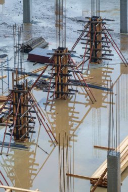 İnşaat alanındaki su birikintisine yansıyan küflenmiş sütunlar