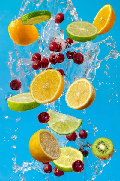 Falling fresh mixed fruits. Slices of the lemon, orange, lime, kiwi and cherry with fresh water in the air. Flying fruits concept.