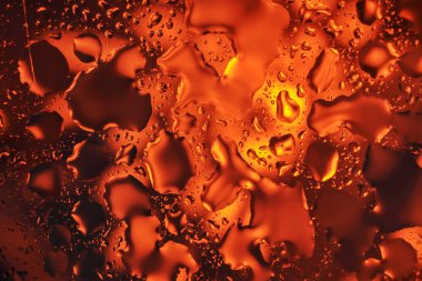 Su rengarenk kırmızı, sarı ve turuncu renklere sahip soyut bir arkaplana düşer