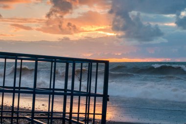 Gün batımında kayalık sahildeki boş metal kafesin ayrıntıları.