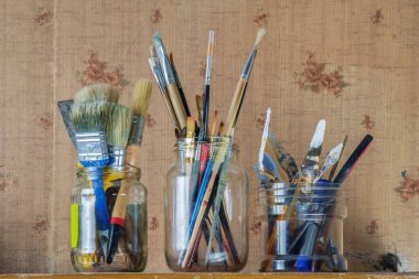 Cam kavanozda boya fırçaları, boyacılar bıçaklar ve sanat aletleri..