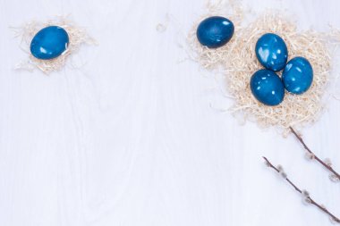 Mavi uzay galaktik Paskalya yumurtaları beyaz ahşap arka planda yuvada. Yaklaş, düz yat. Paskalya tebrik kartı.