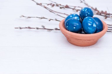 Mavi uzay galaktik paskalya yumurtaları beyaz ahşap arka planda kil plaka içinde. Kapatın. Paskalya tebrik kartı. Boşluğu kopyala.