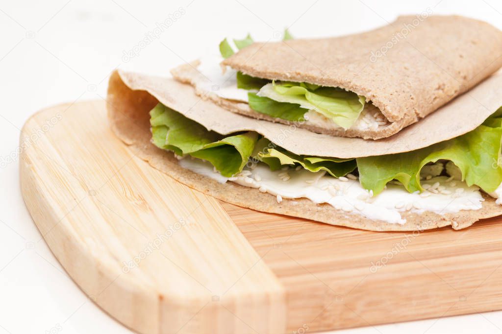 Breakfast or lunch pancakes with cheese, sesame, lettuce on wooden board.
