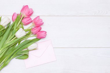 Bahar pembe laleleri ve beyaz ahşap arka planda boş kağıt kartlar. Anneler Günü konsepti. Düz yat, boşluğu kopyala.