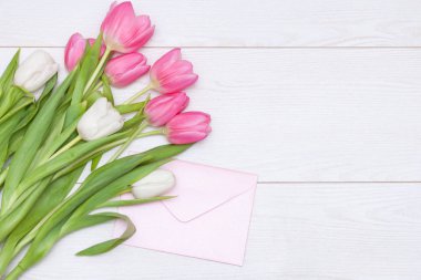 Bahar pembesi laleler, beyaz ahşap arka planda boş kağıt kartlar. Anneler Günü konsepti. Düz yat, boşluğu kopyala.