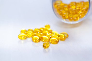 D vitamini içeren sarı kapsüller, beyaz ahşap zemin üzerinde güneş ışığı olan balık yağı omega 3. Sağlıklı ve tıbbi konsept.
