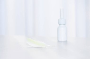 Tüy ve sprey. Kuş tüyü alerjisi, papağan konsepti. Alerjenler.