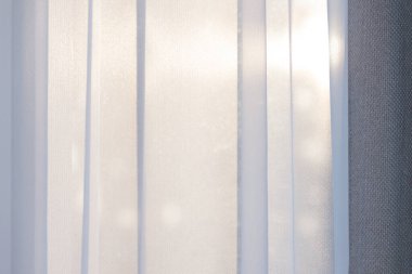 Parlak sabah ya da akşam güneşi perdelerden içeri girer.