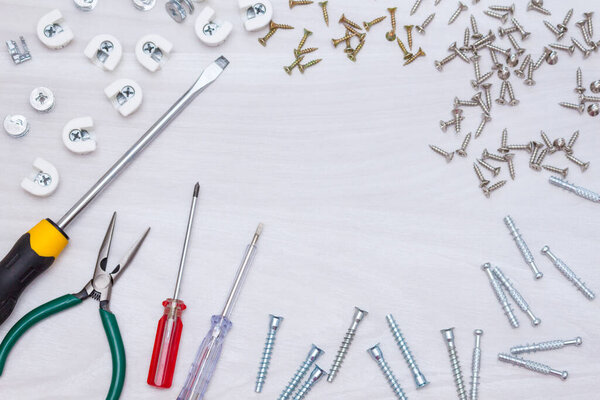 Screw bolts, screwdrivers, furniture assembling on white wooden background, Flat lay, copy space.