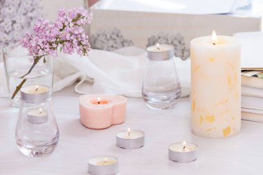 Pastel oda dekoru, yanan el yapımı mumlar, kitaplar, çiçekler. Rahat ve rahat konsept.