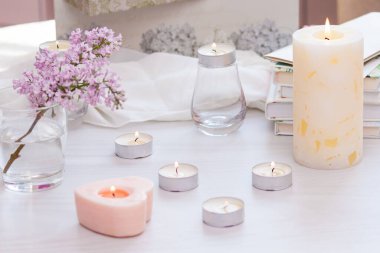 Pastel oda dekoru, yanan el yapımı mumlar, kitaplar, çiçekler. Rahat ve rahat konsept.