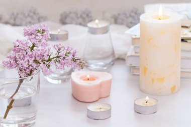 Pastel oda dekoru, yanan el yapımı mumlar, kitaplar, çiçekler. Rahat ve rahat konsept.