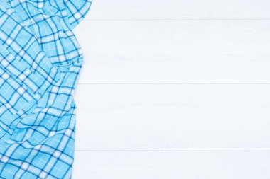 Aşçılık geçmişi, üst görüş konsepti. Beyaz ahşap arka planda mavi ekose piñafore. Boşluğu kopyala.