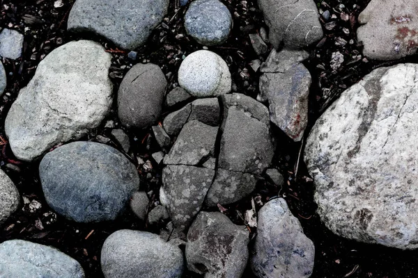 Kulaté říční kameny a popraskané kamenné pozadí — Stock fotografie