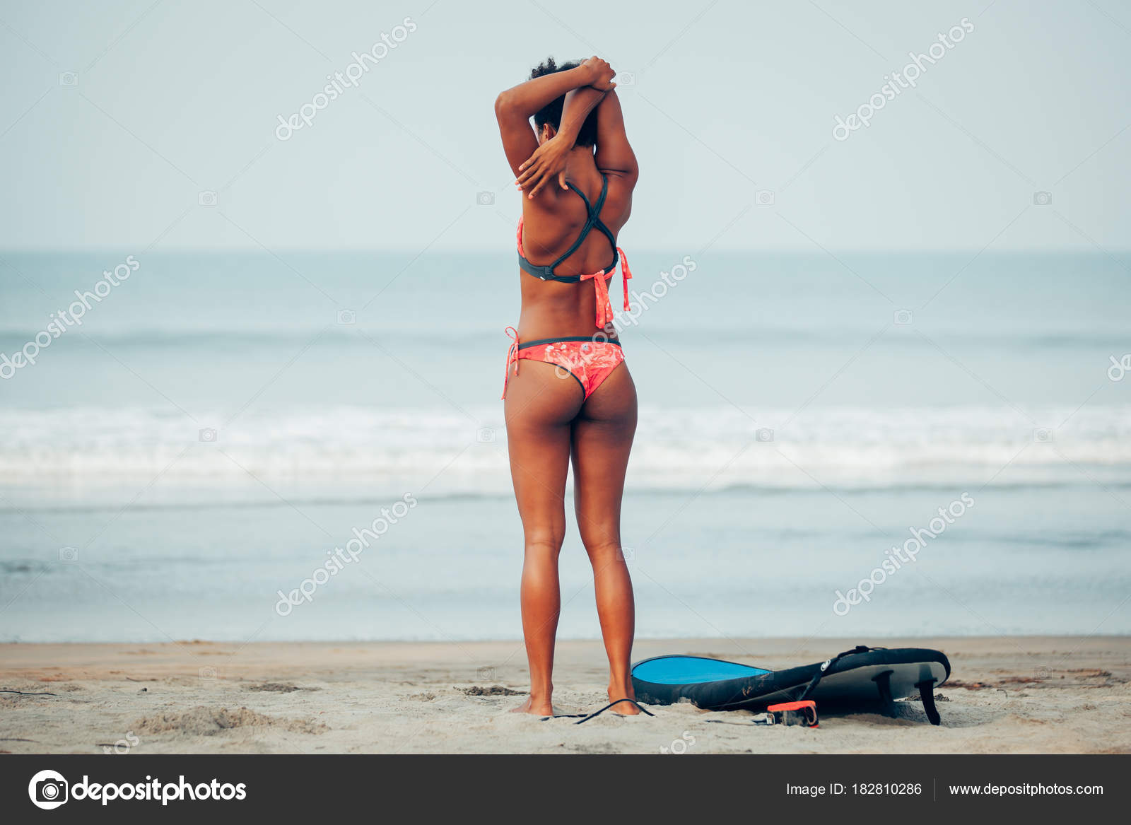 araffed woman in a red bikini laying on the beach , with big