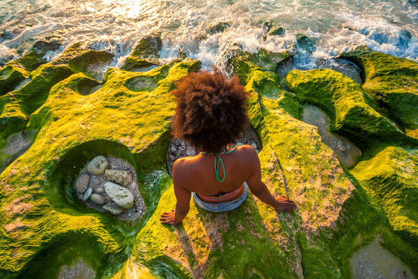 Melanesian pacific islander athlete girl with strong arms on coral reef at sunset