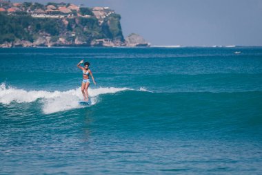 Pasifik Adalı melanesian Papua sörfçü kız plajda Padang Padang, Bali, Endonezya berrak suda mavi longboard sörf afro saç modeli ile